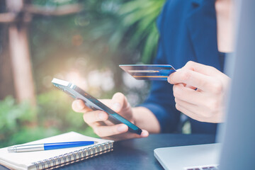 Wall Mural - Woman hand uses a cell phone and credit card to manage online shopping.