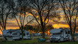 Campers at campsite in winter at sunset with no leaves on the trees