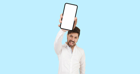 Man with mobile phone jumping with excitement wearing white formal shirt on a aqua background. Happy man flying and jumping in air and showing big mobile empty screen for copy space and advertising.