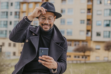 Wall Mural - elegant man in hat on the street with mobile phone