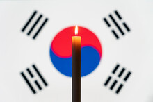 Mourning In The Country. Burning Candle On The Background Of The South Korea Flag. Victims Of Cataclysm Or War Concept. Memorial Day, Remembrance Day. National Mourning.