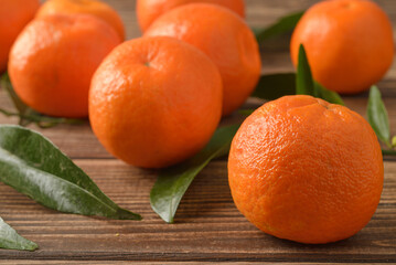 Wall Mural - Tangerines with green leaves on wooden background