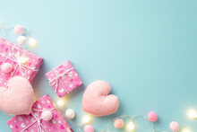 Valentine's Day Concept. Top View Photo Of Present Boxes Light Bulb Garland Soft Heart Shaped Toys And Fluffy Pompons On Isolated Pastel Blue Background With Copyspace