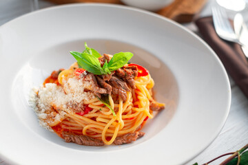 Wall Mural - Spaghetti pasta with tomato sauce and beef stew, tomatoes, parmesan cheese and fresh basil on a wooden background. Italian cuisine, close up