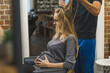 © PoppyPix - Pregnant woman at hairdresser salon. Soon-to-be mother young adult caucasian woman sitting on hairdresser chair and having professional hairstylist changing her hair. High quality photo