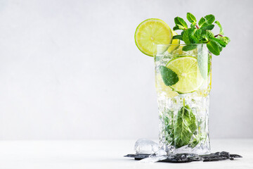 Wall Mural - Mojito classic summer alcoholic cocktail with lime, white rum, soda, cane sugar, mint, and ice in highball glass on gray background. Copy space