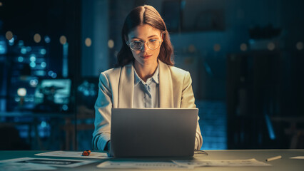 Aufkleber - Stylish Female in Glasses Working on Laptop Computer in a Company Office in the Evening. Young Manager Browsing Internet, Shopping Online and Reading Social Media Posts from Friends and Colleagues.