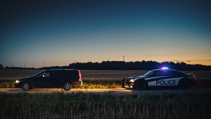 Speeding Driver Gets Pulled Over By Police Patrolling Car During Sunset. Wide Shot of the Two Cars Stopped in a Road Crossing an Open Field. Drunk Driver Gets Caught by Professional Officers