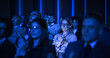 © Gorodenkoff - Young Woman Sitting in a Crowded Audience at a Business Conference. Female Attendee Cheering and Clapping After a Motivational Keynote Speech. Auditorium with Young Successful Businesspeople.