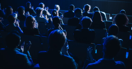 crowd of smart tech people applauding in dark conference hall during a motivational keynote presenta