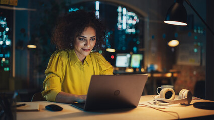 Creative Multiethnic Female Working on Laptop Computer in a Company Office. Happy Project Manager Browsing Internet, Writing Tasks, Developing a Marketing Strategy for Clients.