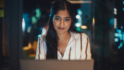 Aufkleber - Young Diverse Accountant Working in the Office Late in the Evening. Positive Female Using Laptop Computer, Preparing Job Assignment and Corporate Report for Finance Director.