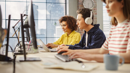 Poster - Multiethnic Group of Creative Colleagues Working on Computers in a Modern Bright Office. A Biracial Woman Smiles Happily After Successfully Finishing a Work Project. Asian Man Using Headphones