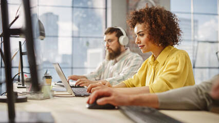 Aufkleber - Portrait of Creative Biracial Woman Focused on Work While Using a Laptop in a Busy Office. Female Graphic Designer Studying Design Briefs and Making Notes.