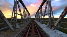 POV Of Walking On Iron Bridge At Sunset. Abandoned Old Railway Bridge. Rusty Metal Bridge With The Sky In The Colors Of The Sunset In The Background. 