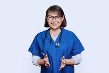 Wall Mural - Portrait of middle aged doctor in uniform looking at camera on white background