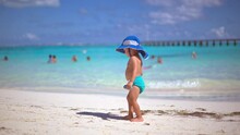 Little Baby Boy With Turquoise Diapers And A Blue Hat Standing On The Beach Watching The Sea Holding A Blue Car In Cancun Mexico
