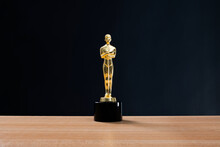 Golden Statuette Trophy On Wooden Table