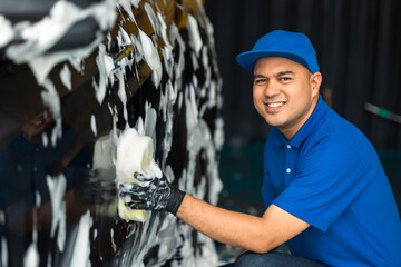 Wall Mural - Man worker washing car service with foam and sponge. Car wash cleaning wipe station. Employees clean a vehicle professionally.