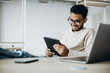 © Petro - Indian business man sitting in office working on a laptop
