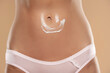 © vladimirfloyd - Close-up partial view of woman with body cream on belly on a beige background