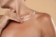 © vladimirfloyd - Woman apply body cream lotion on her chest on a beige background