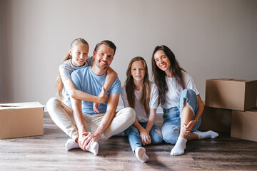 Happy family with two daughters with cardboard boxes in new house at moving day