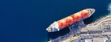 Aerial Drone Top Down Ultra Wide Panoramic Photo Of LNG (Liquified Natural Gas) Tanker Anchored In Small Gas Terminal Island With Tanks For Storage