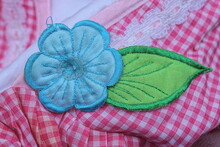 Detail From A Patch In The Form Of A Blue Flower In A Green Sheet Of Fabric On A Red White Matter Of Clothing