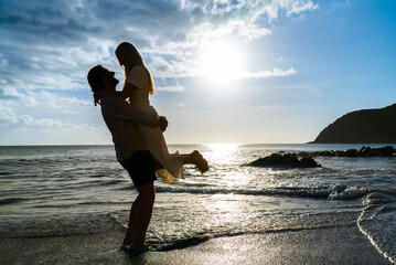 Boyfriend lifting his girlfriend up on an island beach on sunny day