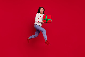 Sticker - Full length photo of cool excited lady wear white sweater jumping running holding gift isolated red color background