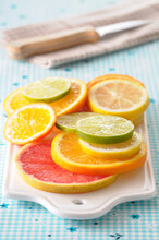 Close-up Of Slices Of Citrus Fruits On Cutting Board On Blue Background