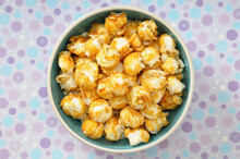 Overhead View Of Caramel Popcorn In Bowl On Purple Polka Dot Background, Studio Shot
