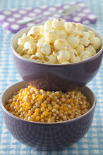 Bowls Of Corn Kernels And Popcorn On Blue Gingham Background, Studio Shot