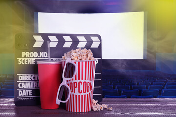 Delicious popcorn, drink, 3D glasses and clapperboard on wooden table in cinema, space for text