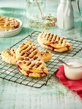 Grilled Fruit Turnovers Drizzled With Icing On A Cooling Rack On A Green Background