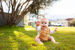 © Austockphoto - Happy baby with hand up giving high five outside on grass