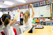 © Austockphoto - Two Students with Hands Up on iPads in Classroom