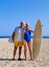 Couple Standing On Beach Holding Surf Boards