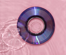 Cd Disk In Pink Water With Shadows. Top View