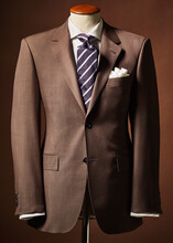 Brown Suit Jacket On Bust With Handkerchief And Tie On Brown Background