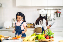 Portrait Of Enjoy Happy Love Asian Family Mother And Little Asian Girl Daughter Child Having Fun Help Cooking Food Healthy Eat Together With Fresh Vegetable Salad And Sandwich Ingredient In Kitchen