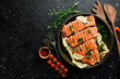 Grilled salmon fillets sprinkled with fresh herbs and lemon juice. On a black background.