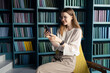 © muse studio - A smart female student with glasses uses an app on her phone to communicate during a break.
