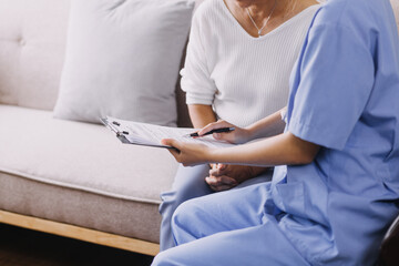 Homecare nursing service and elderly people cardiology healthcare. Close up of young hispanic female doctor nurse check mature caucasian man patient heartbeat using stethoscope during visit