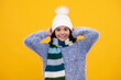 © Olena - Beautiful winter kids portrait. Teenager girl posing with winter sweater and knit hat on yellow background. Happy girl face, positive and smiling emotions.
