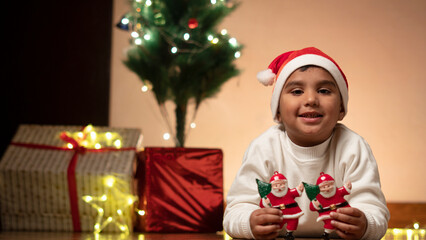 Wall Mural - child boy with christmas tree wearing santa cap 