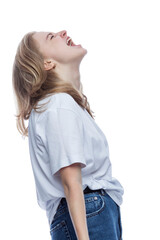 A teenage girl screams. Young pretty blonde in a white T-shirt and jeans. Depression and horror. Isolated on white background. Vertical. Side view.