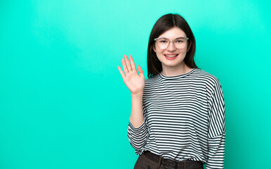 Wall Mural - Young Russian woman isolated on green background saluting with hand with happy expression