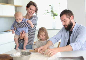 Young parents playing with children in the kitchen